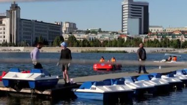 İşçiler nehir kıyısındaki iskelede duran sandalları kontrol ediyor.