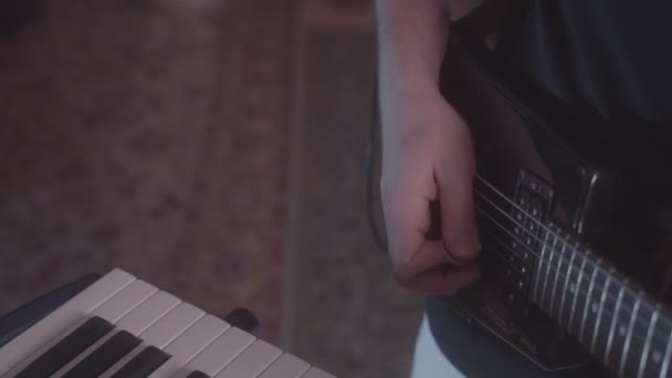 Músico toca guitarra eléctrica cerca del sintetizador en cuarto oscuro — Vídeo de stock