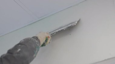 Sıvacı malayı düzgün bir şekilde duvardan duvara yayıyor. Sıvalama işlemi ham maddeyi zarif bir iç yapıya dönüştürür