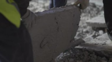 Yoğun beton bölümü koruyucu eldivenlerle odaklanmış ekip tarafından taşındı. İnşaat ekibi tamamlanmamış bina zemininde büyük bir levha taşıyor.