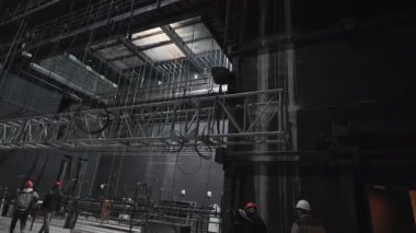 Sahne arkası metal kirişlerle dolu teknik atmosfer yaratıyor. Sallanan kirişler büyük gösteriler için ışık ve dekorasyonları destekliyor