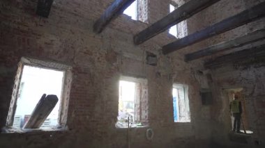 Boş pencereleri ve açıkta duran çelik kirişleri olan tamamlanmamış bina sessiz duruyor. Tozlu hava, sert esintiyi içi boş çerçeveden geçirir.