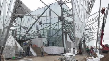 Gelecekçi cam yapısı gri bulutlu gökyüzüne karşı yükseliyor. Üçgen enstalasyonlar, kentsel mimari yenilikler için dışavurumsal ortam yaratıyor