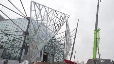 Cam üçgenler cesurca dış cepheden çıkıyorlar ve gotik fütüristik ritim yaratıyorlar. Yapı dram zarafeti ve anıtsallığı vurguluyor