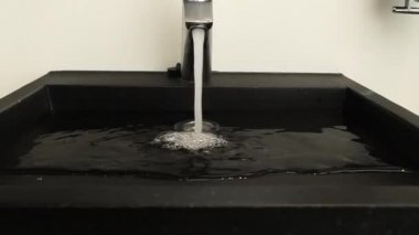  Krom çelikten banyo musluğundan su akar. Yaklaş, yavaşça yakınlaş. Güçlü su akışı 