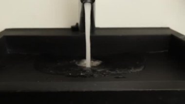 Krom çelikten banyo musluğundan su akar. Yaklaş, yavaşça yakınlaş. Güçlü su akışı