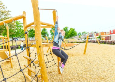 Seçici odaklanma. Kız çocuk parkında tırmanıyor ve kayıyor. Mutlu çocuklar oyun oynuyor ve oyun alanında eğleniyor.