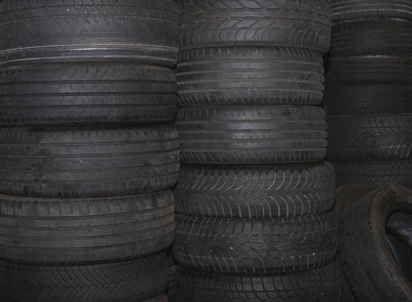 Old used car tires stacked on top of each other. Selective focus. Closeup view. Blurred backgroun