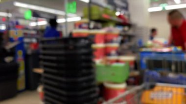 Mavi. Yaklaş. Alıcı, marketteki kasanın yanındaki konveyör bandındaki sepetteki yiyecekleri yerleştiriyor.