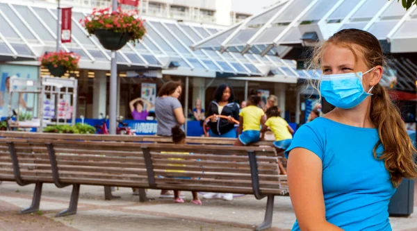 A young girl wears a face mask on the streets of the city.Cute Teenage Girl with a surgical mask on her face that protects against the spread of coronavirus disease.