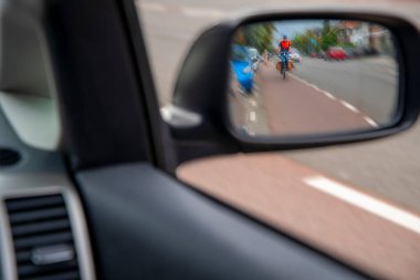 Bulanık odaklı fotoğraf. Şehir trafiğindeki bisikletli insanlar arabanın yan aynasına bakarlar. Şehir yolunda bisikletçiler. 