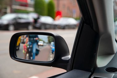 Bulanık odaklı fotoğraf. Şehir trafiğindeki bisikletli insanlar arabanın yan aynasına bakarlar. Şehir yolunda bisikletçiler. 