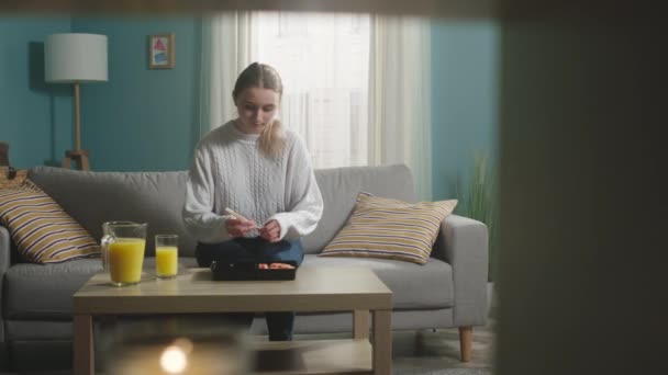 Jong meisje met blond haar komt kamer binnen waar sushi op tafel ligt — Stockvideo