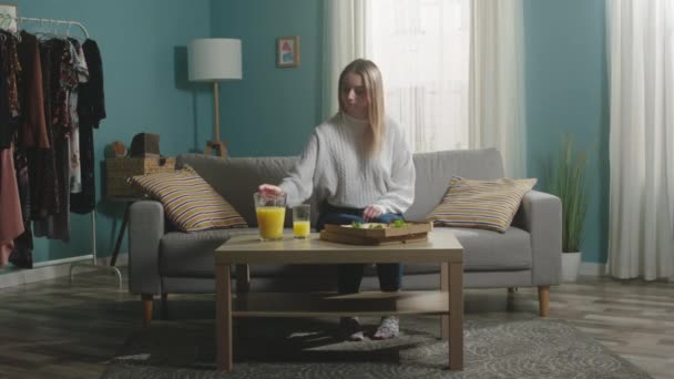 Chica en chaqueta blanca vierte vaso de jugo de naranja — Vídeos de Stock