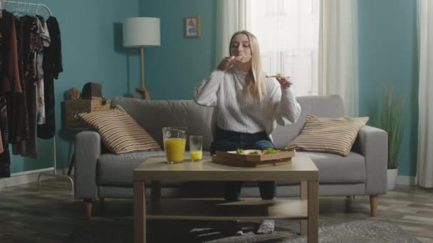 Jong meisje eet twee stukken pizza uit de doos — Stockvideo