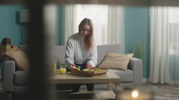 Meisje in een witte jas eet pizza — Stockvideo