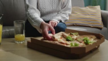 Beyaz kazaklı kız bir dilim İtalyan pizzası yiyor.