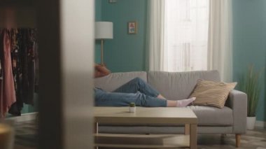 Genç kız kanepede uzanıyor ve endişeyle telefonda konuşuyor.