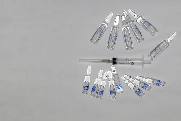 Group of ampoules and injection syringe on a textile white background. Copy space. On big ampoules the inscription in Russian: \