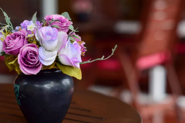 Üflenmiş bir masadaki vazodaki pembe kumaştan çiçekler. Kahve dükkanında, klasik renk tonunda.