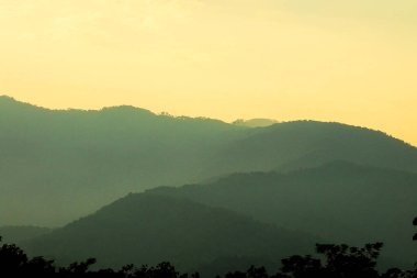 Arkaplanda gökyüzü olan dağların üzerinden gün doğumu