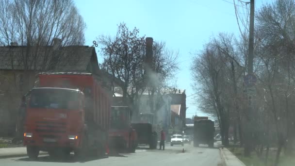 俄罗斯，萨马拉2019年4月20日：马克西姆高尔基街，一辆卡车倒入沥青到汽车铺路。工人们在公路上铺了沥青。溜冰场平滑热沥青. — 图库视频影像