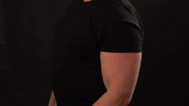 Yakın adam dambılla egzersiz yapmaktır. Siyah arka plan üzerinde dambıl ile Kaslı adam eğitimi.