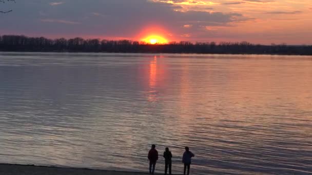 美丽的夕阳在大河上 城市的居民过着积极的生活方式 在日落后的大河堤上工作了一天 从最后一次的水中反射黄金 — 图库视频影像