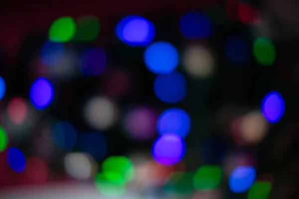 A árvore de Natal é iluminada em cores diferentes. Fundo borrado do feriado de ano novo — Fotografia de Stock