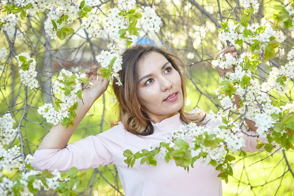 girl with flowers. gorgeous model in the spring garden. the girl near the tree in the spring. the concept of spring.