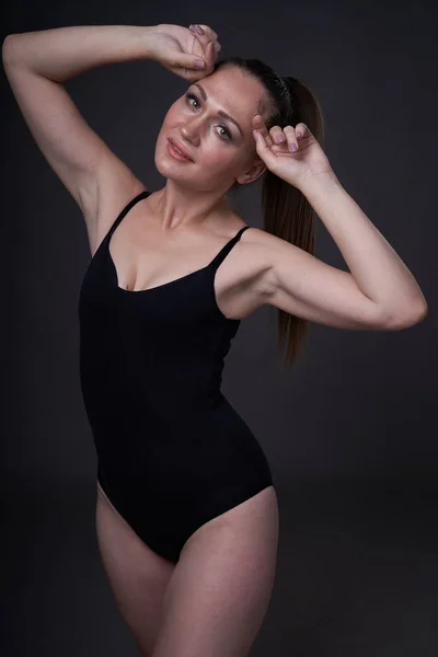 Rugalmas szexi lány jelent a fekete szürke háttér a berendezési ruhák Baud — Stock Fotó