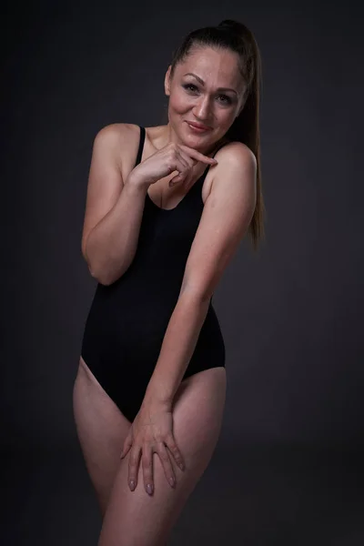 Гнучка сексуальна дівчина позує на чорному сірому фоні в пристосованому одязі — стокове фото