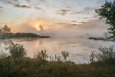 Güneşli puslu bir ışıkta gölün üzerinde sessiz bir şafak. Sonbahar zamanı.