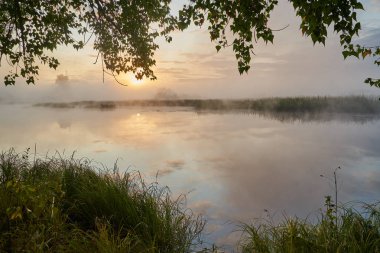 Güneşli puslu bir ışıkta gölün üzerinde sessiz bir şafak. Sonbahar zamanı.