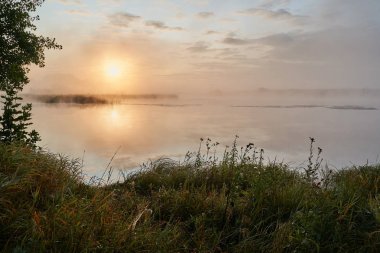 Güneşli puslu bir ışıkta gölün üzerinde sessiz bir şafak. Sonbahar zamanı.
