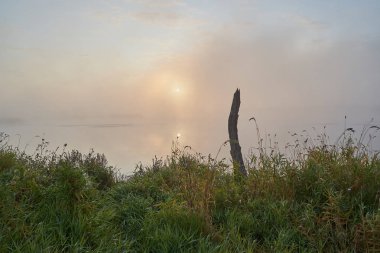 Güneşli puslu bir ışıkta gölün üzerinde sessiz bir şafak. Sonbahar zamanı.