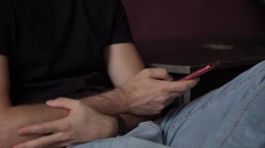 Genç beyaz yetişkin elinde bir akıllı telefon hücresi tutarak ve parmaklarıyla bir metin mesajı yazarak