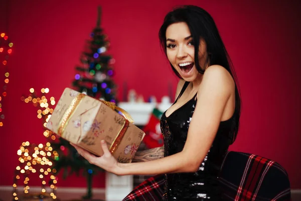Glückliche junge Dame mit Geschenken zu Weihnachten. Neujahrskonzept. Weihnachtsbaum, Geschenke und Geschenkschachteln darunter. Neujahrsschmuck. — Stockfoto
