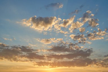 Gün batımında parlayan parlak ışık bulutlarıyla güzel bir akşam masmavi gökyüzü. Gün batımında sıcak bir yaz akşamı. Parlak gün batımı.