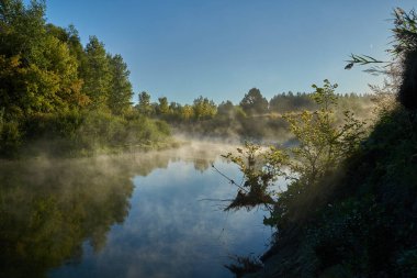 Sonbahar geldi. Nehrin üzerinde sisli, kara kara düşünen bir sis içinde şafak. Sabahın erken saatlerinde sisle kaplı güzel bir orman ve nehir manzarası. Güneş ışınları..