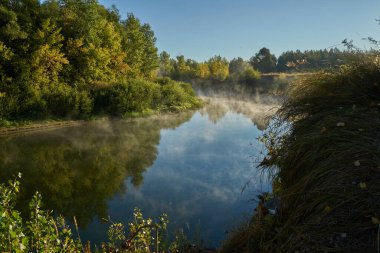 Sonbahar geldi. Nehrin üzerinde sisli, kara kara düşünen bir sis içinde şafak. Sabahın erken saatlerinde sisle kaplı güzel bir orman ve nehir manzarası. Güneş ışınları..