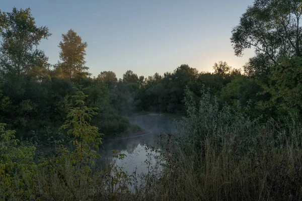 秋の時間だ 霧の中で川の上で夜明け ぼんやりとした霞 早朝に霧に覆われた森と川の美しい景色 太陽の光の光線 — ストック写真