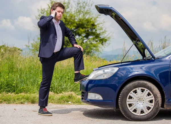 A broken car on the road, a man talks to a cell phone and calls for help on the road