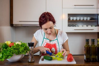 Mutfakta genç bir kız, yüzüne gülümse, öğle yemeği pişir, çeşitli sebzeler hazırla, marul, brokoli, mutfak, kız mutfakta, Cassia sebzeleri.