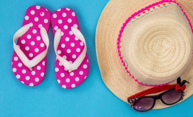 Mavi arka planda plaj aksesuarları, plaj terlikleri, şapka, gözlükler. Boşluğu kopyala, metin alanını. Denizde tatiller