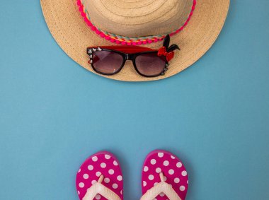 Mavi arka planda plaj aksesuarları, plaj terlikleri, şapka, gözlükler. Boşluğu kopyala, metin alanını. Denizde tatiller
