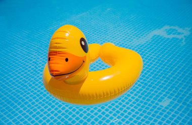 Kaygısız ve güvenli bir yaz havuzu üzerinde çocuk için turkuaz mavi suda yüzerken mutlu olmak için can kurtaran lastiği sarı ördek