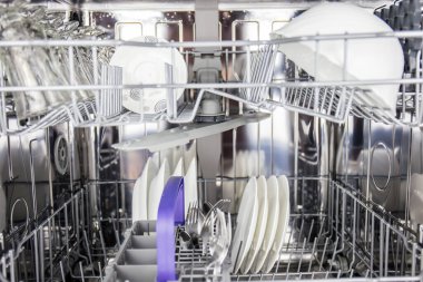 Bulaşık makinesine istiflenmiş tabaklar sıcak su, sabun ve modern elektrikli bulaşık makinesi kullanılarak parlak ev halkı için deterjan ile lekelerden temizlenecek.