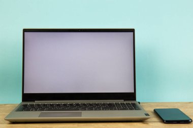 Masaüstünde beyaz ekran olan dizüstü bilgisayar, mavi arkaplan. İş ve finans