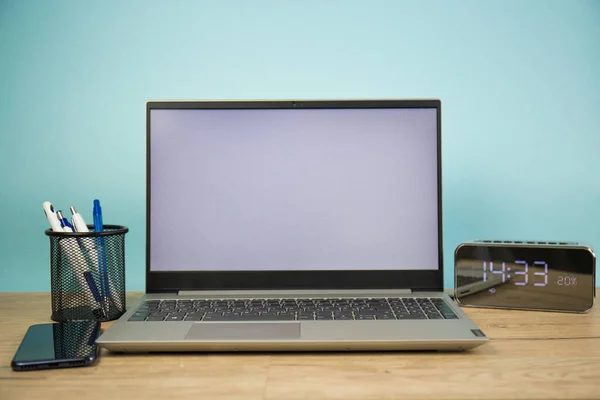 Laptop computer with a white screen on the desktop, blue background. Business and finance
